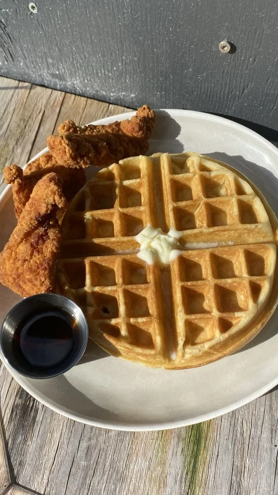 Crispy chicken tenders over a golden Belgian waffle with syrup.