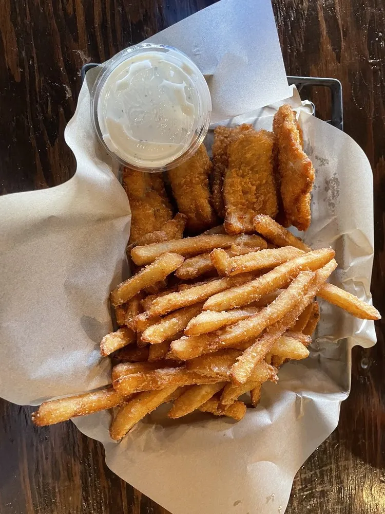 A basket of crispy panko-crusted fish and chips with fries and house tartar.